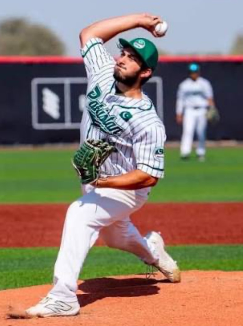 Pakistan pitcher delivering in white pinstripe uniform