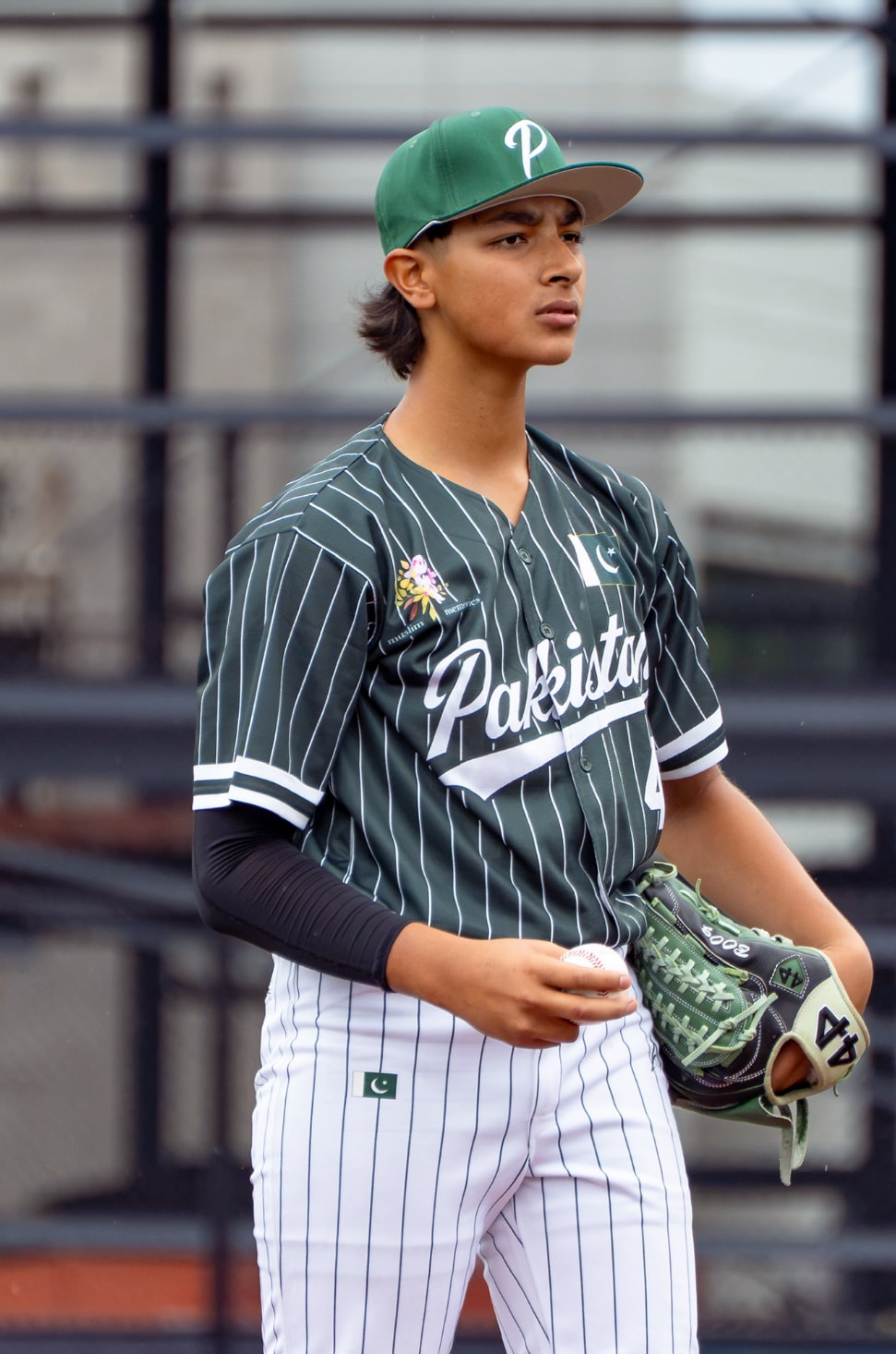 Pakistan player in dark green pinstripe jersey holding ball