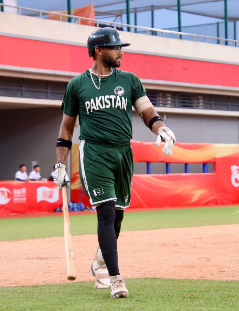 Pakistan player in green uniform walking with bat